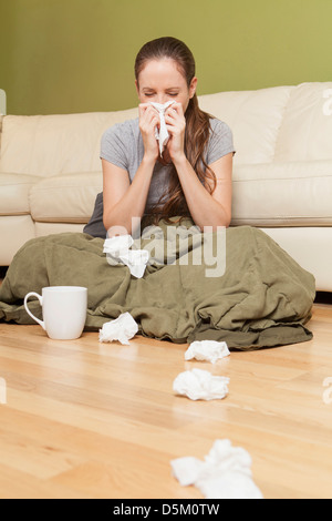 La donna nel salotto soffia il naso Foto Stock