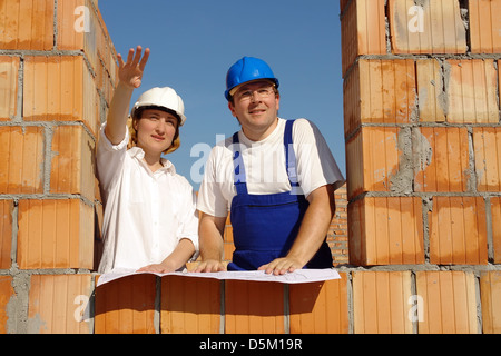 Investitore femmina che mostra il gestore del sito casa sua nozione in piedi in un muro di mattoni di apertura della finestra Foto Stock