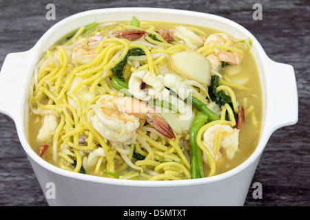 Hokkien Mee Stir Fry giallo tagliatelle con gamberi calamari Fishcake e verdura verde Foto Stock