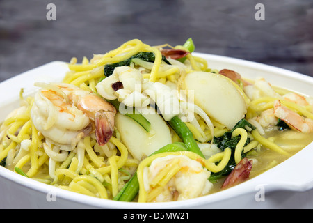 Hokkien Mee Stir Fry giallo tagliatelle con gamberi calamari Fishcake e verdura verde Vista laterale Vista dettagliata Foto Stock