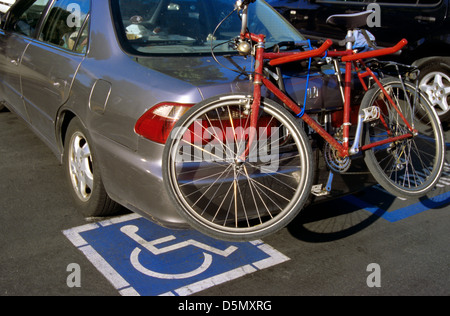 Auto con bicicletta attaccata alla porta-bici parcheggiata in una zona di handicap Foto Stock