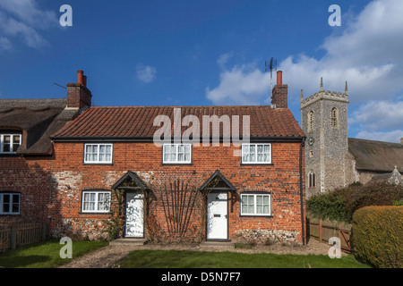 Un affascinante villaggio bungalow in Woodbastwick e dal tetto in paglia St Fabian & San Sebastian Chiesa, Norfolk, Inghilterra, Regno Unito Foto Stock