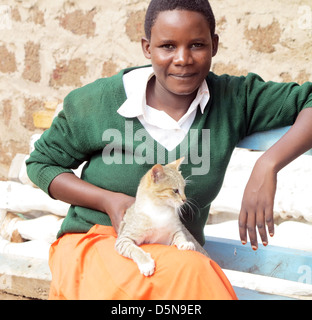 Giovani ragazze adolescenti in uniforme scolastica e un gatto sul suo ginocchio che posano per una telecamera in Moshi;Tanzania;East Africa;l'Africa Foto Stock