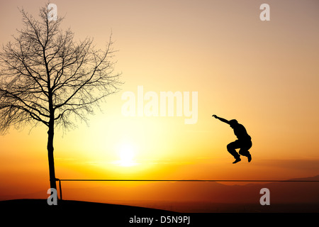 Silhouette di uomo sulla slackline in sunset Foto Stock
