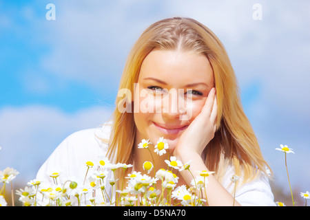 Closeup ritratto di dolce ragazza bionda sulle bianche margherite glade, godendo di estate natura, relax e concetto di vacanza Foto Stock