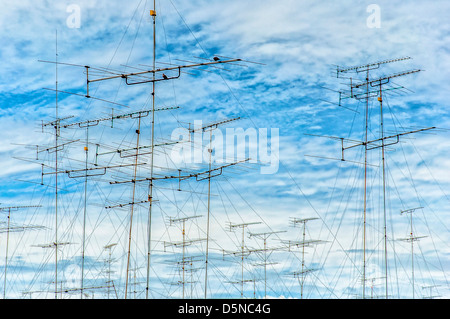 Una raccolta della televisione analogica antenne impostata su uno sfondo di cielo blu e nuvole whispy. Foto Stock