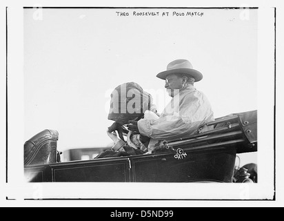 Una fotografia del presidente Theodore Roosevelt che assiste ad una partita di polo negli anni '1910, indossando un cappello e una sciarpa, con un'automobile d'epoca nelle vicinanze. Foto Stock