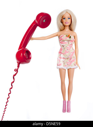 Bambola Barbie, tenendo in mano un telefono rosso ricevitore. Isolato su bianco. Foto Stock