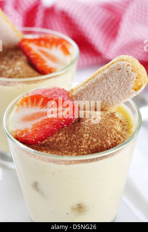 Tradizionale dolce italiano tiramisù in un bicchiere con fragole su sfondo di legno Foto Stock