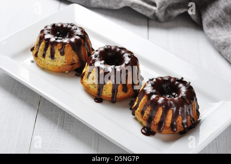 Torta con fuso chokolate ciliegina sul piatto bianco su sfondo di legno Foto Stock