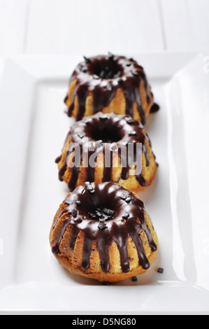 Torta con fuso chokolate ciliegina sul piatto bianco su sfondo di legno Foto Stock