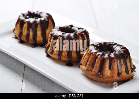 Torta con fuso chokolate ciliegina sul piatto bianco su sfondo di legno Foto Stock