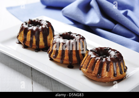 Torte con fuso chokolate ciliegina sul piatto bianco su sfondo di legno Foto Stock