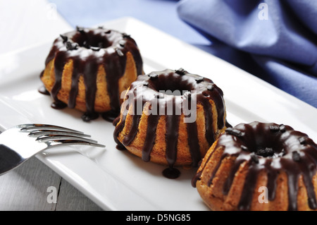 Torta con fuso chokolate ciliegina sul piatto bianco su sfondo di legno Foto Stock