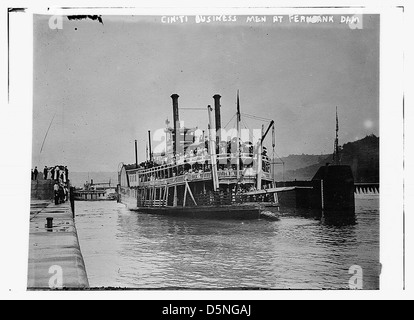 Questa foto raffigura uomini d'affari di Cincinnati presso la diga di Fernbank negli anni '1910, forse a bordo di una barca o di un motoscafo, che cattura l'attività del tempo vicino alla diga, con un battello a vapore e un traghetto in vista. Foto Stock