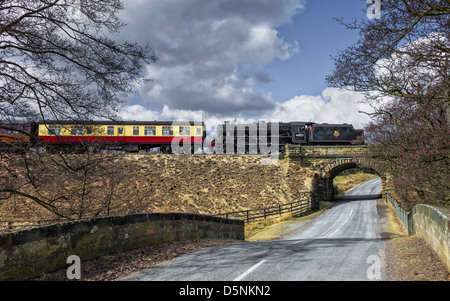 Vintage treno a vapore che attraversa tradizionale di pietra il ponte di arco in North York Moors National Park vicino a Goathland, nello Yorkshire, Regno Unito. Foto Stock
