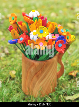 Bouquet artigianato multicolore felice artificiale fiori in un vaso di close-up, legno Foto Stock