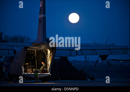 US Air Force airman siede nel retro di un C-130J Hercules aeromobili cargo sotto una luna piena di Marzo 27, 2013 a Little Rock Air Force Base in Arkansas. Foto Stock