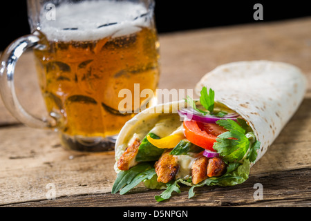 Kebab servito con birra fredda sul vecchio tavolo in legno Foto Stock