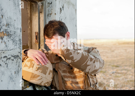 Soldato sofferenza con proprio Disturbo Post-traumatico da Stress sul campo di battaglia. Soldato indossa militare britannico uniforme del deserto. Foto Stock