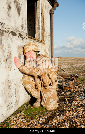 Soldato sofferenza con proprio Disturbo Post-traumatico da Stress sul campo di battaglia. Soldato indossa militare britannico uniforme del deserto. Foto Stock