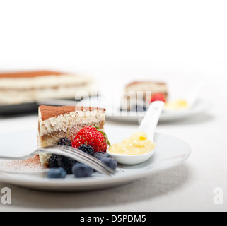 Italiano classico tiramisù dessert con bacche e custartd crema pasticcera sul lato Foto Stock