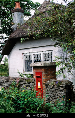 Post rurale scatola incassata in una parete di mattoni nella parte anteriore del tradizionale cottage con il tetto di paglia Foto Stock