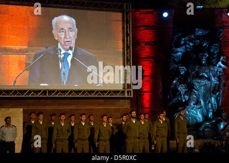 Gerusalemme, Israele. Il 7 aprile 2013. Il Presidente Shimon Peres è proiettata su un enorme schermo al di sopra di un IDF paracadutisti" la guardia d'onore come egli parla alla cerimonia di apertura per olocausto dei martiri ed eroi' giorno del ricordo a Yad Vashem Holocaust Museum. Gerusalemme, Israele. 7-Aprile-2013. Israele commemora olocausto dei martiri ed eroi' giorno del ricordo con una cerimonia di apertura a Yad Vashem Holocaust Museum. Quest'anno il tema centrale è 'Defiance e ribellione durante l'olocausto: 70 anni dopo l'insurrezione del Ghetto di Varsavia'. Credito: Nir Alon / Alamy Live News Foto Stock