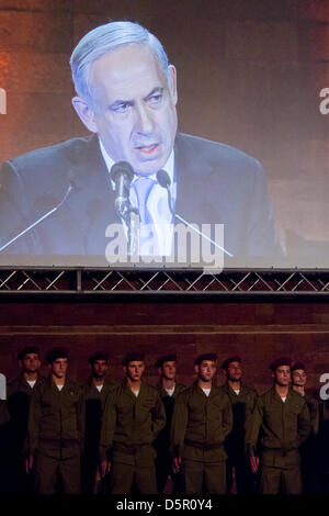 Gerusalemme, Israele. Il 7 aprile 2013. Il primo ministro Benjamin Netanyahu è proiettata su un enorme schermo al di sopra di un IDF paracadutisti" la guardia d'onore come egli parla alla cerimonia di apertura per olocausto dei martiri ed eroi' giorno del ricordo a Yad Vashem Holocaust Museum. Gerusalemme, Israele. 7-Aprile-2013. Israele commemora olocausto dei martiri ed eroi' giorno del ricordo con una cerimonia di apertura a Yad Vashem Holocaust Museum. Quest'anno il tema centrale è 'Defiance e ribellione durante l'olocausto: 70 anni dopo l'insurrezione del Ghetto di Varsavia'. Credito: Nir Alon / Alamy Live News Foto Stock