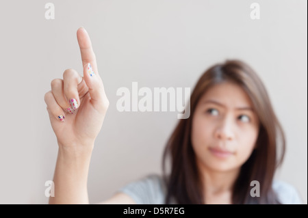 Donna asiatica premendo un pulsante immaginario spazio vuoto per i pulsanti Foto Stock