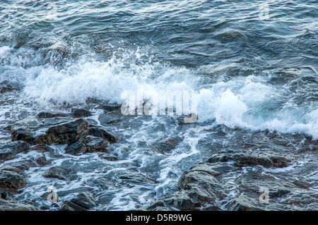 Visto che infuria mare dove le onde che si infrangono sulle rocce Foto Stock