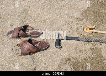 Pantofole e bastoni abbandonati sulla spiaggia sabbiosa Foto Stock