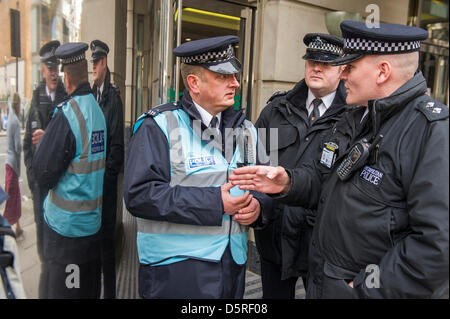 Londra, Regno Unito. Dal 8 aprile 2013. Gli ufficiali di polizia discutere di tattica prima dell'arresto. Anti-road attivisti, noto come la Combe Haven difensori fase pacifica di una due giorni di 'search' del Dipartimento per i trasporti (DFT) per le sue raccomandazioni circa il £100m Bexhill-Hastings Link Road - hanno una copia di un documento con le principali conclusioni redatto, ma il corpo del documento non è molto favorevole del regime proposto. Il 'searchers' ha tentato di inserire il ma erano così formata invece una coda fuori la DfT della porta anteriore. Questa coda è previsto di continuare da 8am - 5pm da lunedì 8 aprile e tu Foto Stock