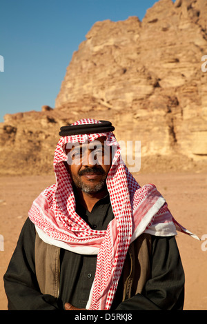 Un beduino uomo che indossa il rosso-e-bianco keffiyeh a scacchi sciarpa a Wadi Rum, Giordania Foto Stock