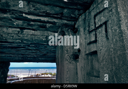 WW2 tedesco pistola concrete bunker con swastika graffiti che si affaccia su spiagge assolate di Fort Mahon Plage Le Touquet Francia Foto Stock