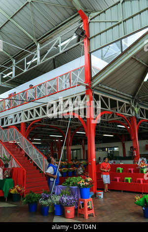 Un operaio usando un rullo di vernice su un lungo palo interno il mercato pubblico di Papeete, Tahiti. Foto Stock