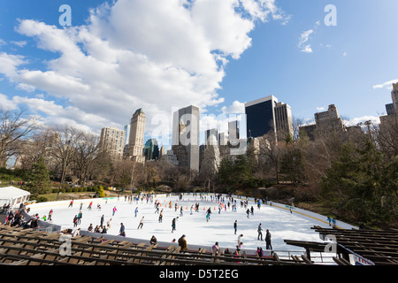 Persone il pattinaggio su un anello di ghiaccio a Central Park di New York City con edifici in background Foto Stock