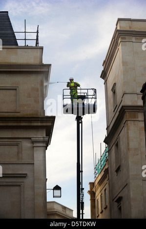 Un builder in un cherry picker spruzzando la facciata del bagno Southgate shopping centre, Somerset REGNO UNITO Foto Stock