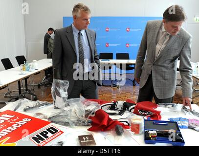 Bassa Sassonia Ministro degli interni di Uwe Schuenemann (R) e Hannover è presidente di polizia Axel Brockmann (L) stand di fronte NPD cartelloni, sequestrati armi e materiale di propaganda dopo una conferenza stampa presso il Ministero degli Interni ad Hannover, Germania, 25 settembre 2012. Bassa Sassonia vietato il più importante neo-nazi gruppo dello stato tedesco. Dal 2008, il gruppo aveva effettuato Foto Stock