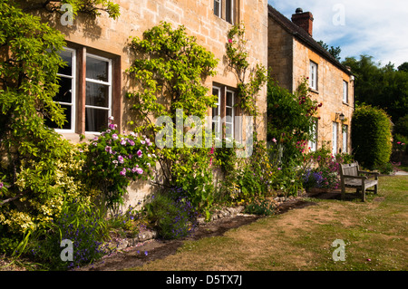 Tipico cottage in pietra accanto al villaggio verde nella pittoresca Cotswold Hills Village di Stanton in Gloucestershire, Inghilterra Foto Stock