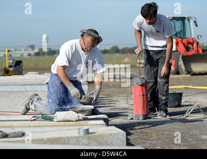 Muratori lavorano su blocchi di granito in campo di Tempelhof di Berlino, Germania, 02 ottobre 2012. Un nuovo impianto per skateboarders viene costruito qui dal vecchio pietre di granito del Palazzo della Repubblica. I bambini sono ammessi a partecipare alla costruzione sotto la supervisione. Foto: BRITTA PEDERSEN (ATTENZIONE: per solo uso editoriale in connessione con la relazione sulla costruzione di Foto Stock