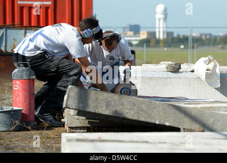 Muratori lavorano su blocchi di granito in campo di Tempelhof di Berlino, Germania, 02 ottobre 2012. Un nuovo impianto per skateboarders viene costruito qui dal vecchio pietre di granito del Palazzo della Repubblica. I bambini sono ammessi a partecipare alla costruzione sotto la supervisione. Foto: BRITTA PEDERSEN (ATTENZIONE: per solo uso editoriale in connessione con la relazione sulla costruzione di Foto Stock