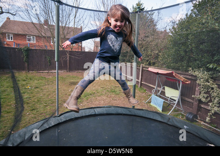 5 anno vecchia ragazza rimbalza su un trampolino da giardino Foto Stock