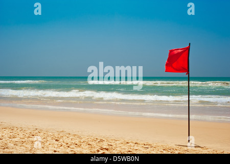 Il nuoto è pericoloso in onde dell'oceano. Red Flag di avviso sbattimenti nel vento sulla spiaggia di maltempo Foto Stock