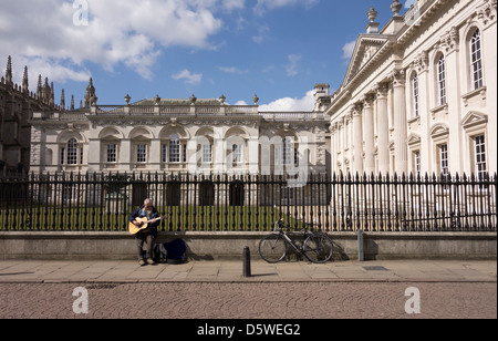Animatore di strada suonando la chitarra nella parte anteriore della vecchia legge le scuole della città di Cambridge Inghilterra Foto Stock