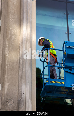 Workman su un cherry picker la riparazione della parte anteriore dell'edificio a Newcastle sul Tyne, Regno Unito Foto Stock