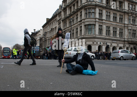 Un manifestante solitario siede nel mezzo di una strada in Westminster, Londra il 30/03/13 Foto Stock