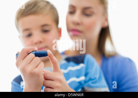 Madre aiutare figlio di prova dello zucchero nel sangue Foto Stock