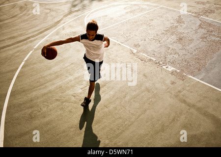 L'uomo giocare a basket su corte Foto Stock