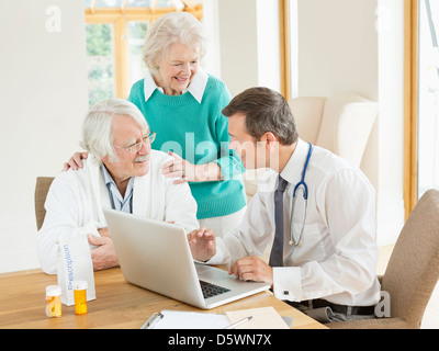 Medico di parlare con i pazienti più anziani a casa chiamata Foto Stock